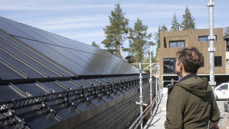 Mann ser ut over et tak med integrerte solceller